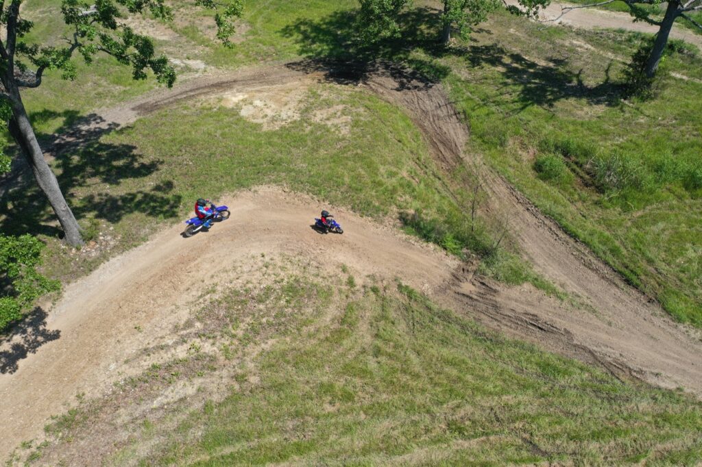 Drone shot of Blue and Arys riding through a corner at a motocross track near Sedalia Missouri